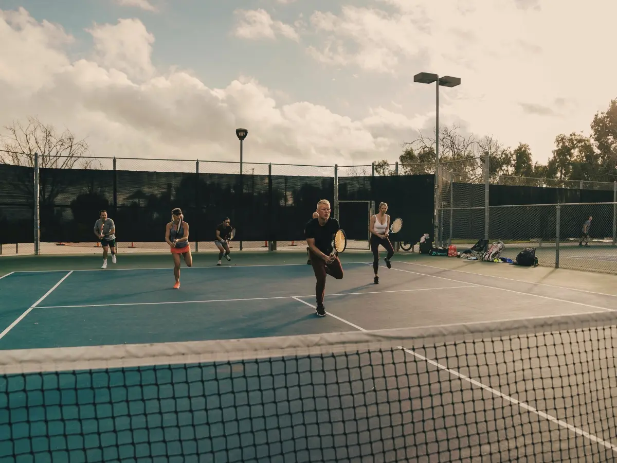 LBTA community group in cardio tennis session under golden-hour lighting